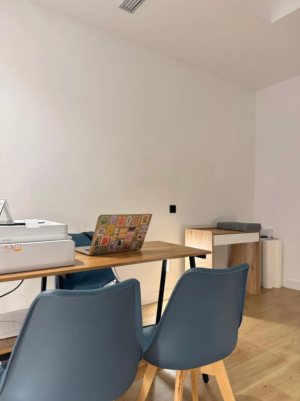 Consultation room with a wooden desk, blue chairs and a laptop