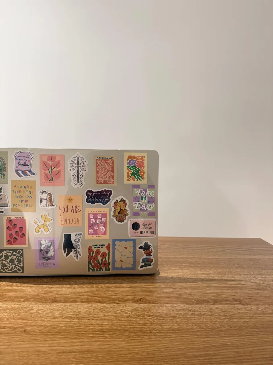 Laptop covered in colourful stickers on the wooden desk